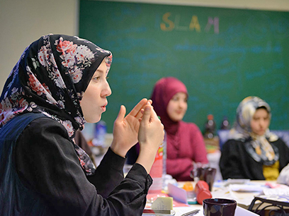 Eine Teilnehmerin erklärt anderen Teilnehmerinnen etwas während eines Seminars.