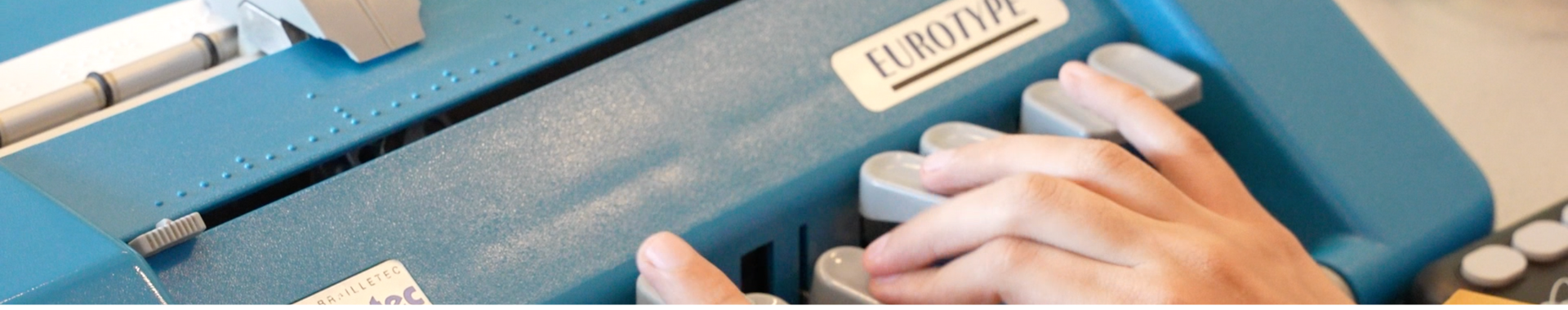 Das Bild zeigt eine blaue Braille-Zeile, die von einer Person bedient wird.