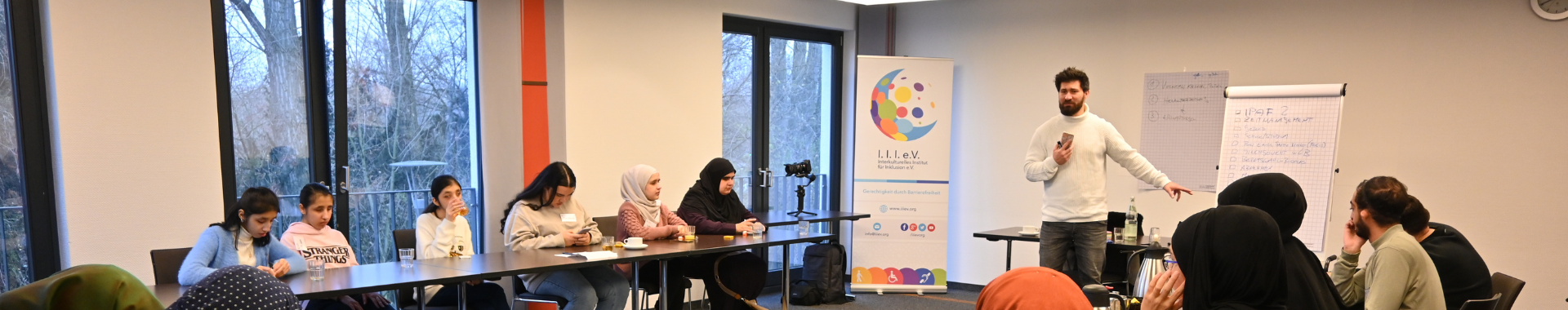 Ein großer Raum, in dem sich über 10 Teilnehmer für ein Seminar befinden und dem Referenten vorne zuhören.